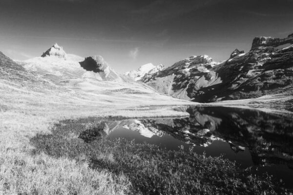 Schwarzweiss-Foto von kleinem Bergsee bei Melchsee-Frutt mit Spiegelung der Berge im See, Wanderung zum Engstlensee.