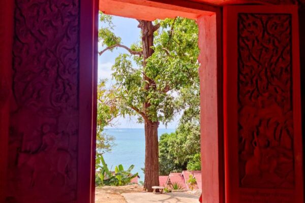 Blick durch ein Fenster des Tempels aufs angrenzende Meer und einen grossen Baum