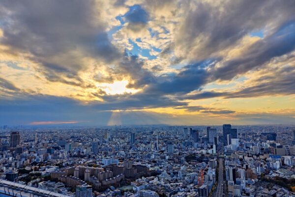 Sonnenuntergang über der Stadt mit Sonnenstrahlen und gelbem Himmel.