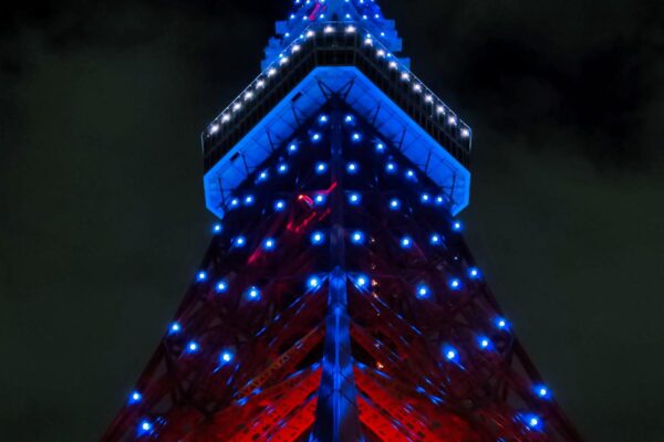 Tokyo Tower Spitze von unten gesehen bei Nacht, der Turm ist rot und blau beleuchtet.