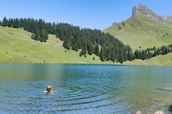 Person schwimmt im Bannalpsee, mit Bergen im Hintergrund